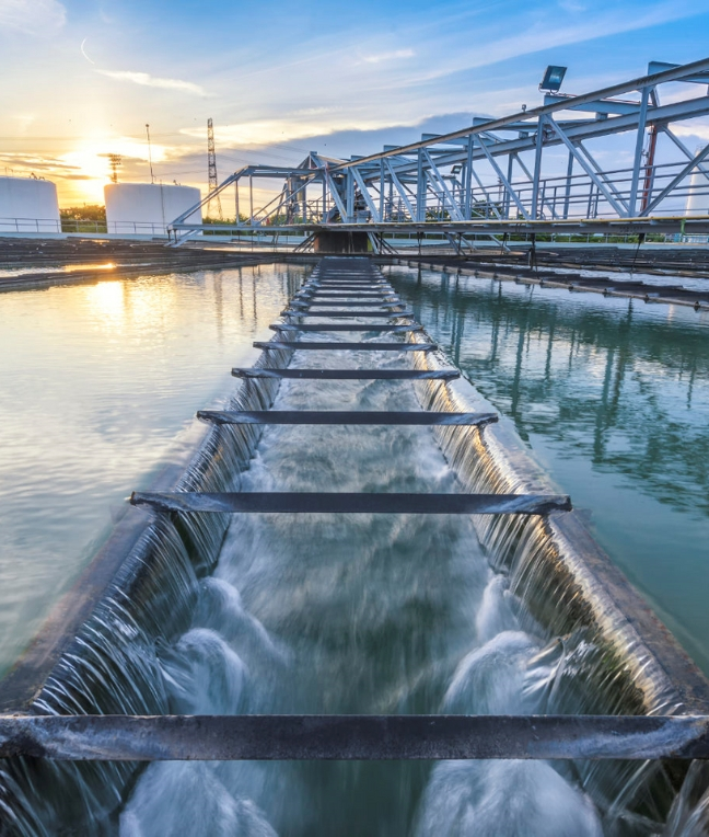 Wasserbehandlungsanlage mit einem abendlichen Himmel und Wasser, das über Rinnen fließt.